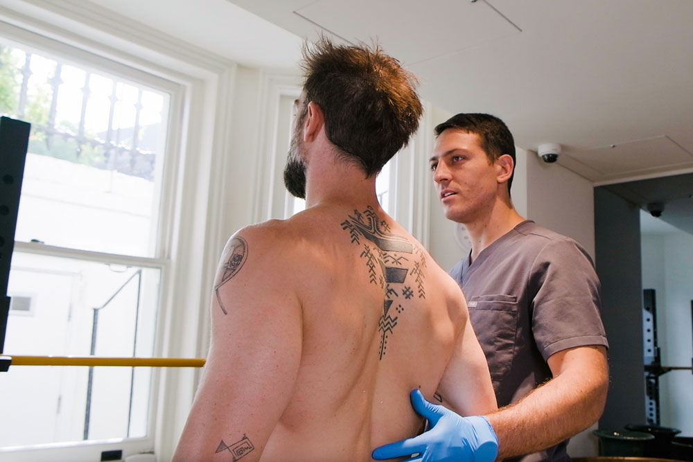 Physiotherapist assessing a patient with lower back pain in a clinical setting