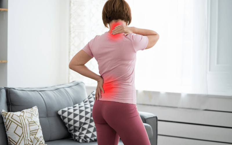 woman with back pain holding her back and neck