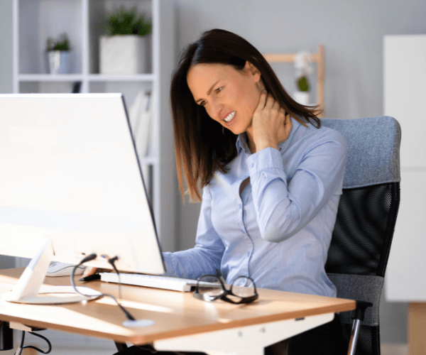Woman sat at her desk with neck pain and needs Physiotherapy for Posture